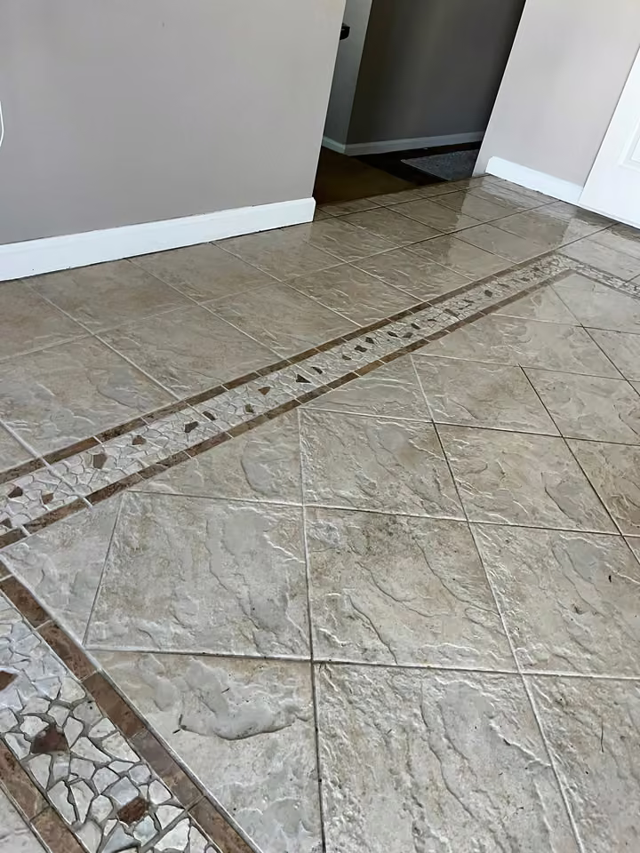 Cleaned tile entryway with grout lines and a decorative mosaic border